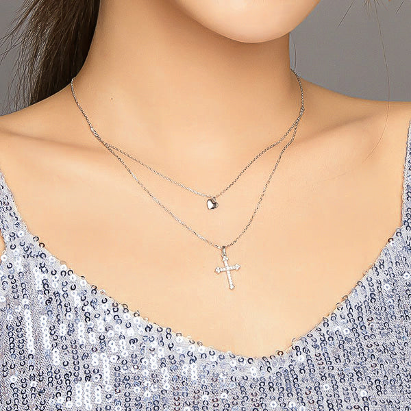 Woman wearing a silver layered heart and cross necklace