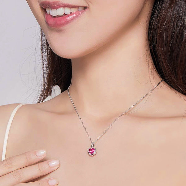 Woman wearing a fuchsia pink crystal heart pendant with protective wings on a silver necklace