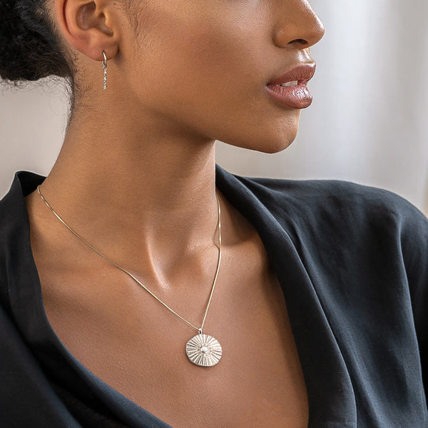 Woman wearing a silver sunrise coin necklace