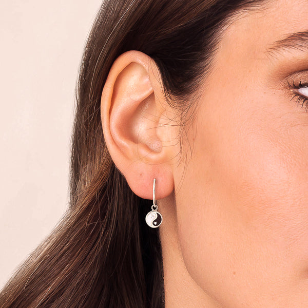 Woman wearing silver yin yang earrings