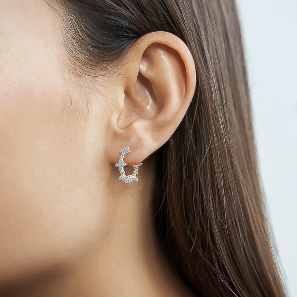 Woman wearing silver floral hoop earrings