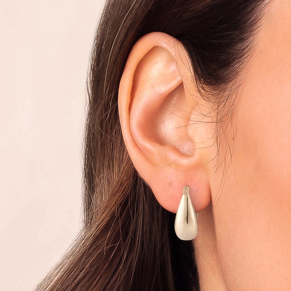 Woman wearing thick silver teardrop hoop earrings