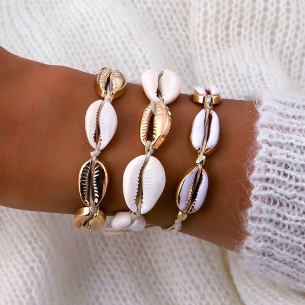White and gold cowrie shell bracelet on a woman's wrist