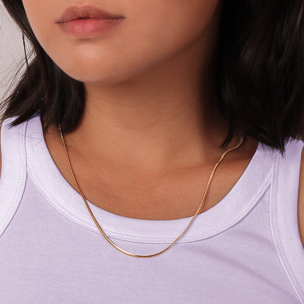 Woman wearing a thin 1.5mm gold snake chain necklace