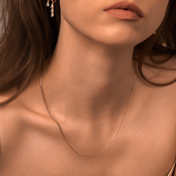 Woman wearing a thin 1.5mm rose gold snake chain necklace