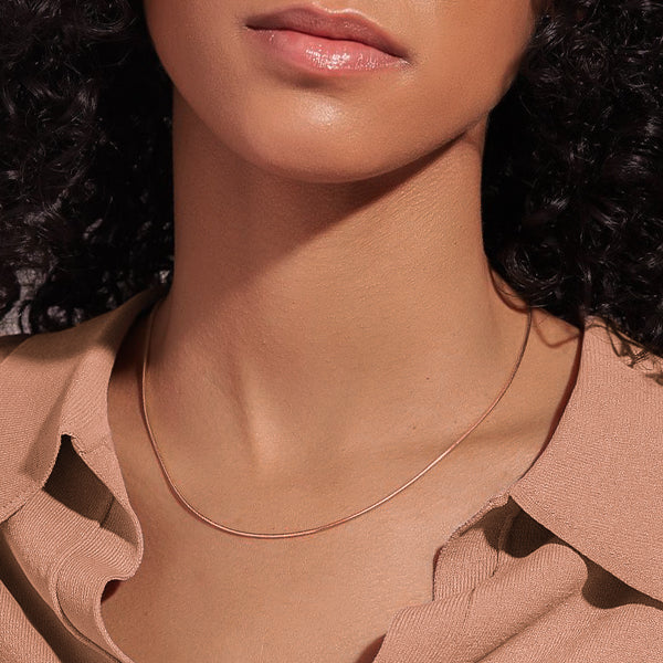 Woman wearing a thin 1mm rose gold snake chain necklace