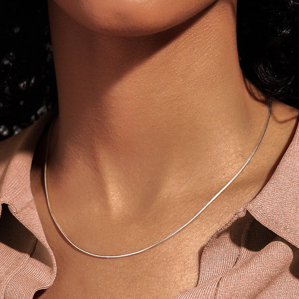 Woman wearing a thin 1mm silver snake chain necklace