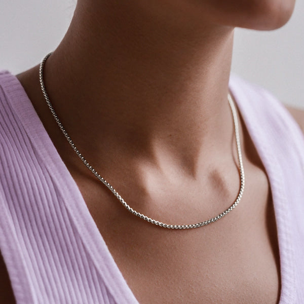 Woman wearing a 2mm silver box chain necklace on her neck