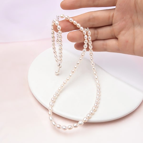 hand holding a 4-5mm mini freshwater pearl choker necklace with oval beads
