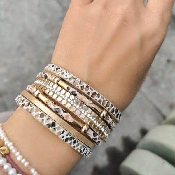 Woman wearing a beige and gold snakeskin leather cuff bracelet on her wrist