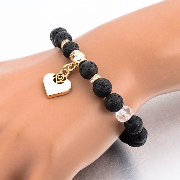 Woman wearing a beaded lava stone bracelet with a gold heart charm