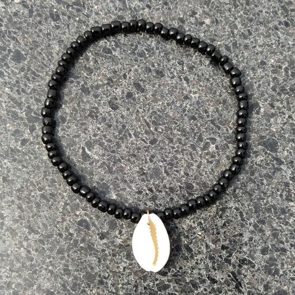 Black beaded seashell anklet on a grey background