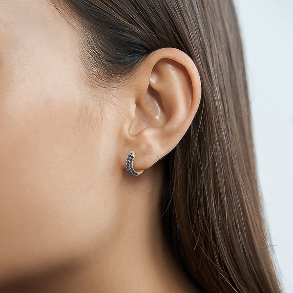 Woman wearing blue cubic zirconia pavé mini hoop earrings