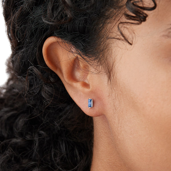 Woman wearing silver and blue mini baguette cubic zirconia stud earrings