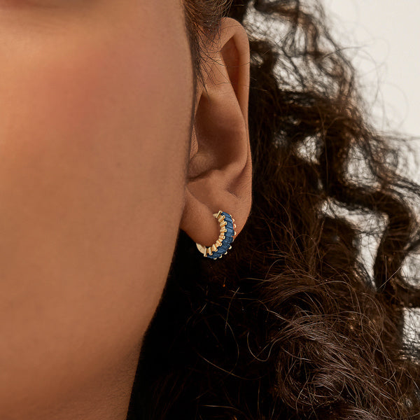 Woman wearing small gold and blue hoop earrings