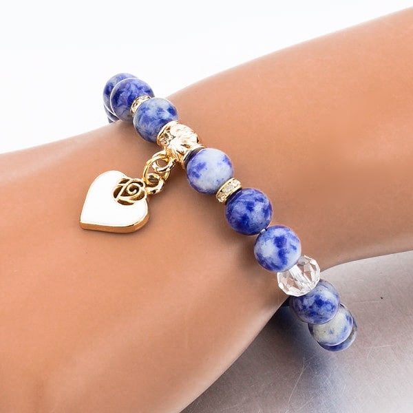 Woman wearing a beaded blue sodalite bracelet with a gold heart charm