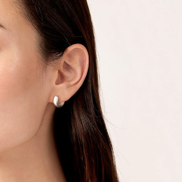 Woman wearing chunky silver huggie hoop earrings