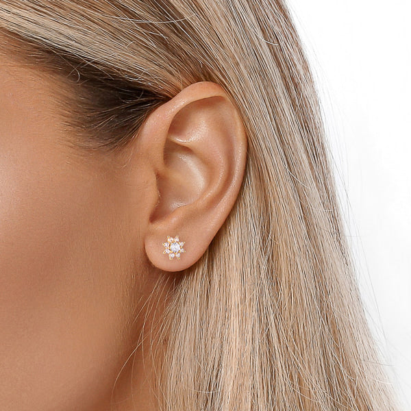 Woman wearing gold crystal flower stud earrings