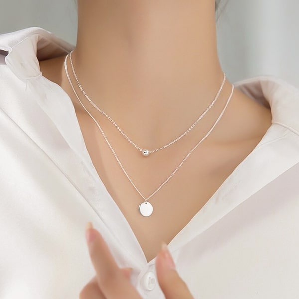 Woman wearing a layered sterling silver coin necklace