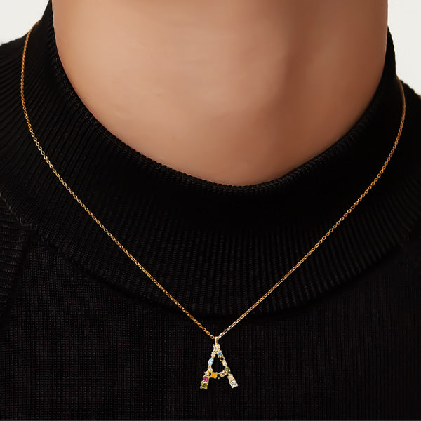 Woman wearing a gold colorful stone initial letter necklace