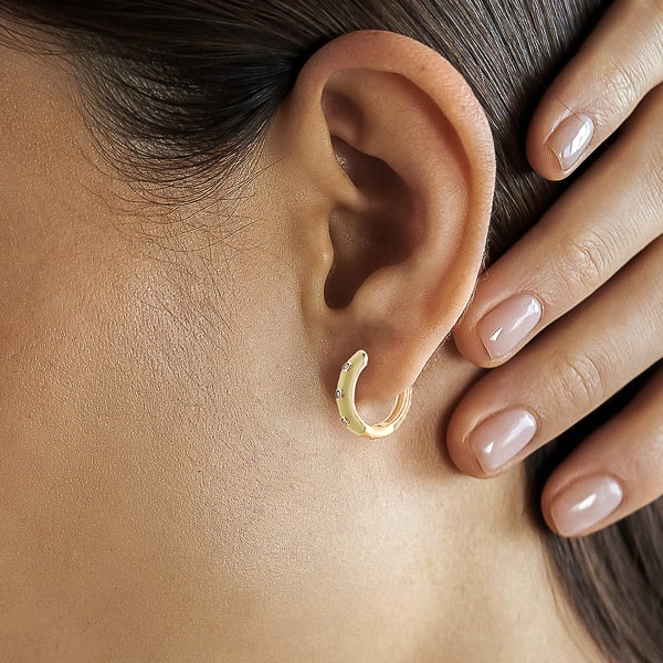 Woman wearing cream enamel mini hoop earrings