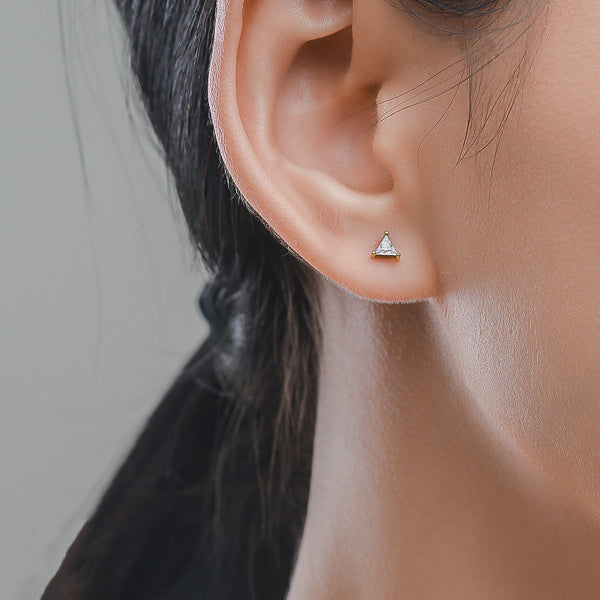 Woman wearing gold triangle cubic zirconia mini stud earrings