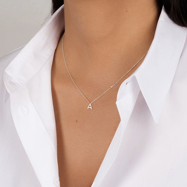 Woman wearing a dainty silver initial letter necklace