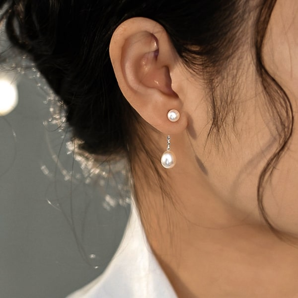 Woman wearing double pearl drop stud earrings