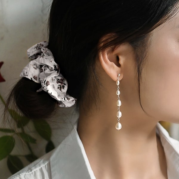 Woman wearing five pearl drop earrings