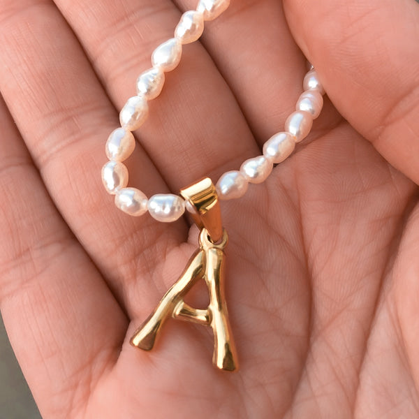 Freshwater pearl necklace with gold initial pendant, closeup photo
