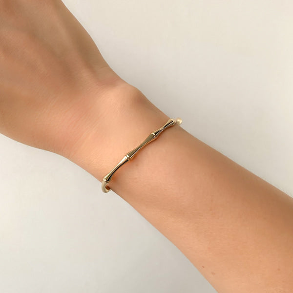 Woman wearing a gold bamboo cuff bracelet on her wrist
