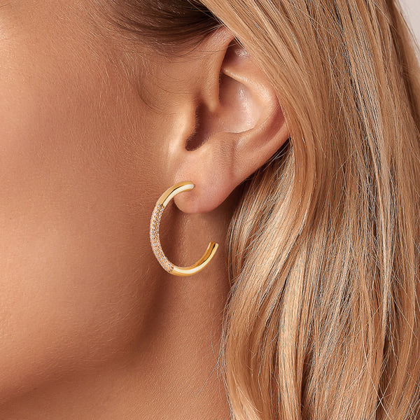 Woman wearing gold cubic zirconia pavé hoop earrings