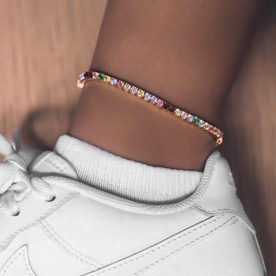 Woman wearing a gold colorful crystal tennis anklet