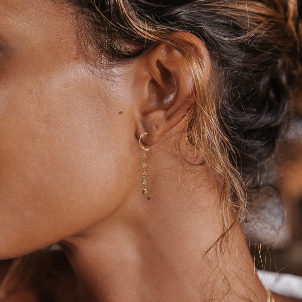 Woman wearing colorful cubic zirconia drop chain hoop earrings