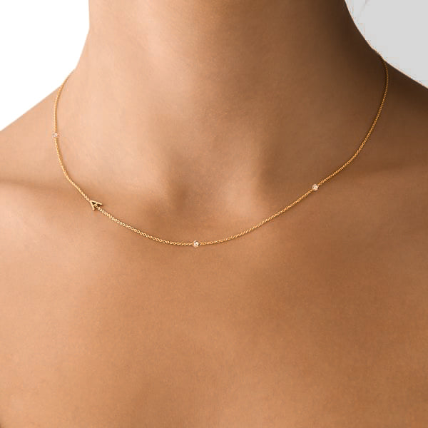 Woman wearing a gold asymmetrical initial letter chain necklace