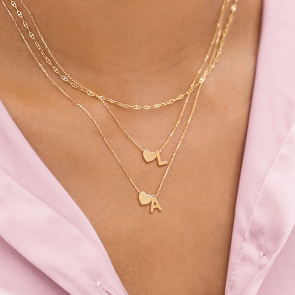 Woman wearing a gold heart initial letter necklace