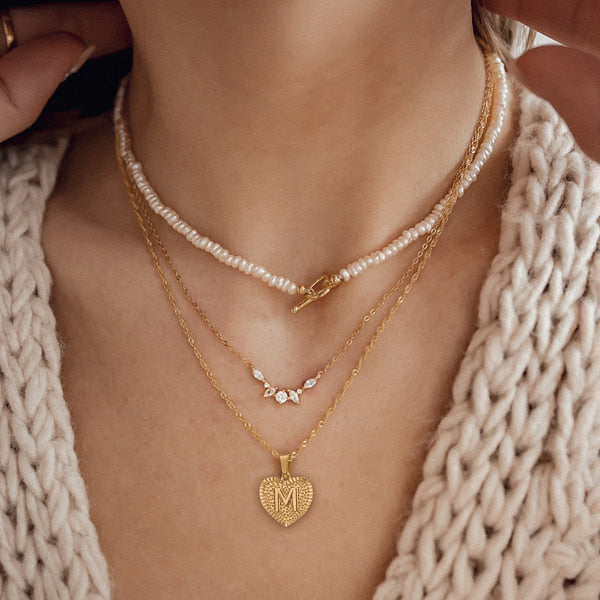 Woman wearing a gold initial heart pendant necklace