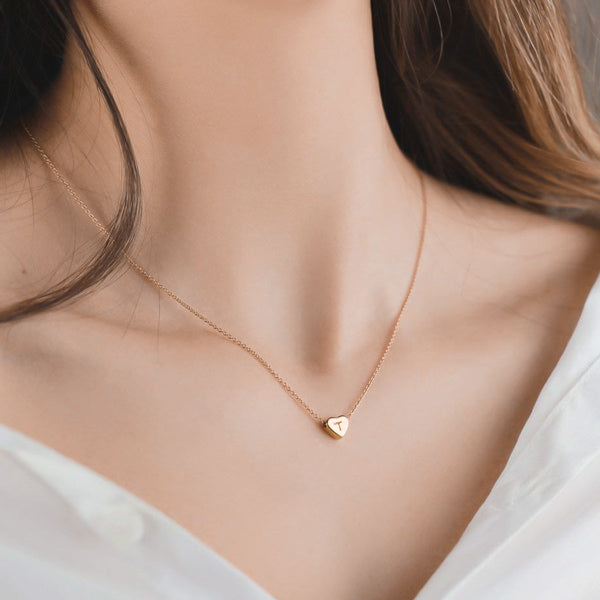 Woman wearing a small gold initial heart necklace
