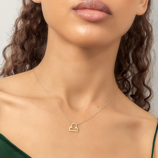 Woman wearing a gold Libra necklace