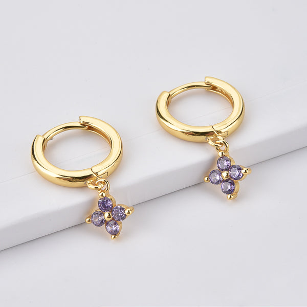 Gold huggie hoop earrings with a dangling purple cubic zirconia flower