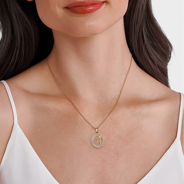Woman wearing a gold initial letter crystal coin pendant necklace