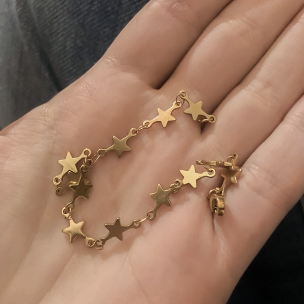 Woman holding a gold star chain bracelet on her hand