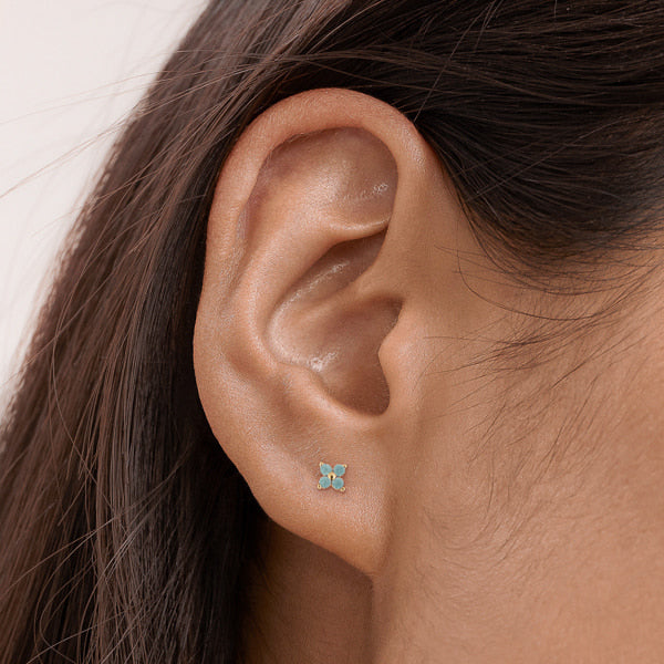 Woman wearing gold and turquoise mini flower stud earrings