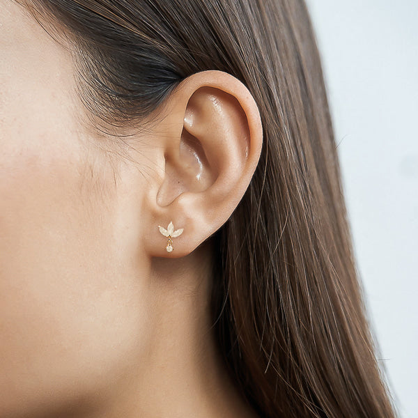 Woman wearing gold and milky white lotus earrings