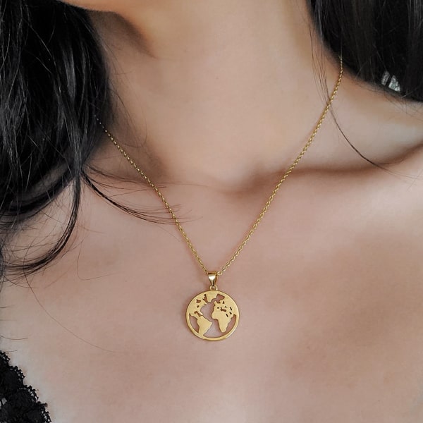 Woman wearing a gold world pendant necklace