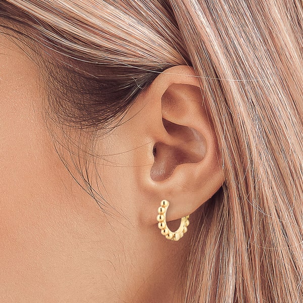 Woman wearing small gold bead hoop earrings