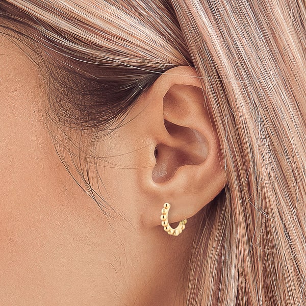 Woman wearing gold bead mini hoop earrings