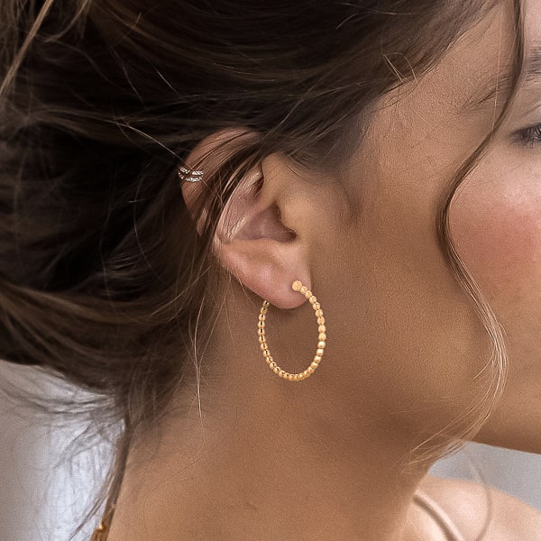 Woman wearing gold beaded hoop earrings