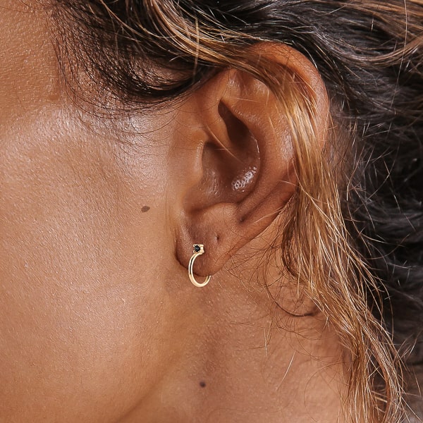 Woman wearing gold black crystal stud huggie hoop earrings