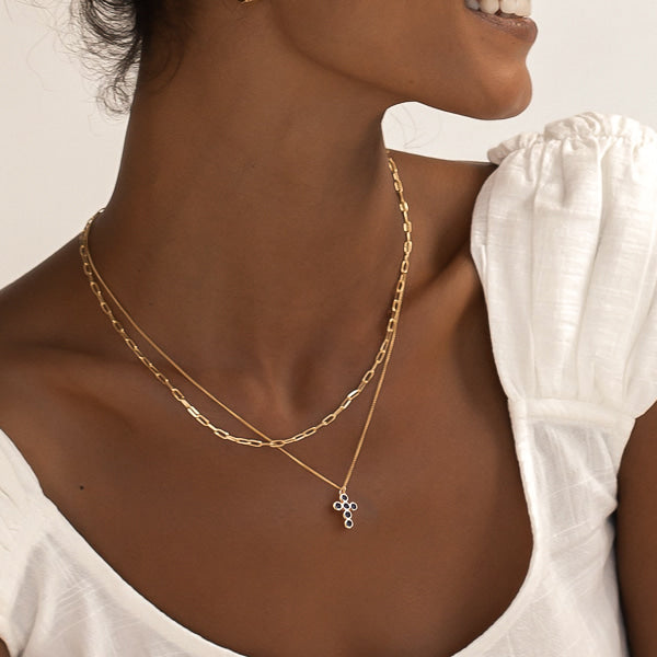 Woman wearing a gold rounded cross necklace with black crystals